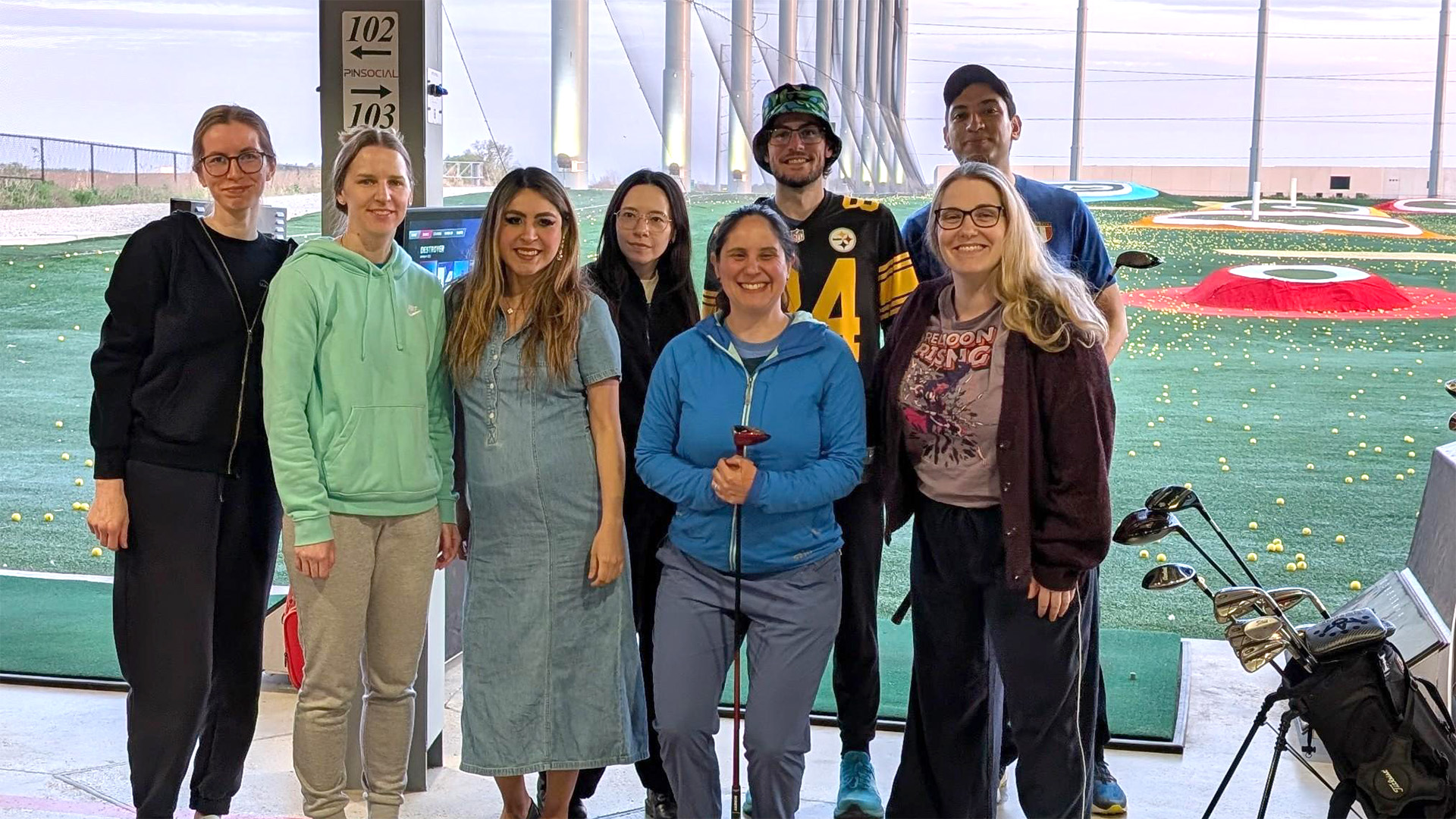 A group of people smiling at a golf range