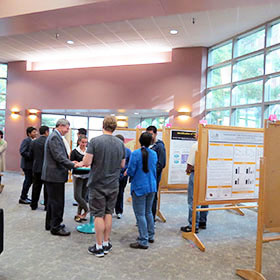 A group of people talking in front of some research posters