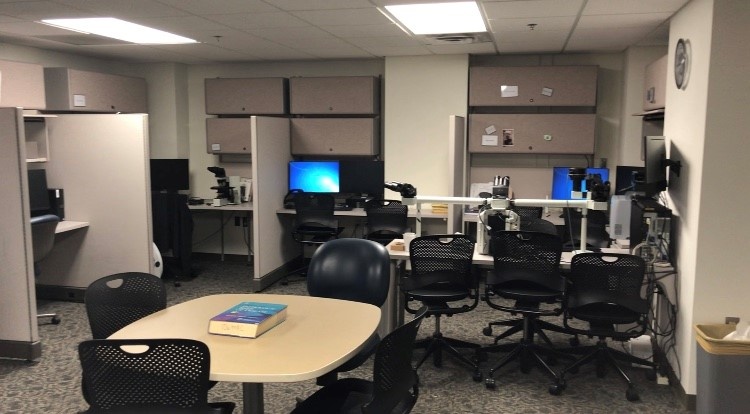 A room with tables chairs, workstations, and other equipment