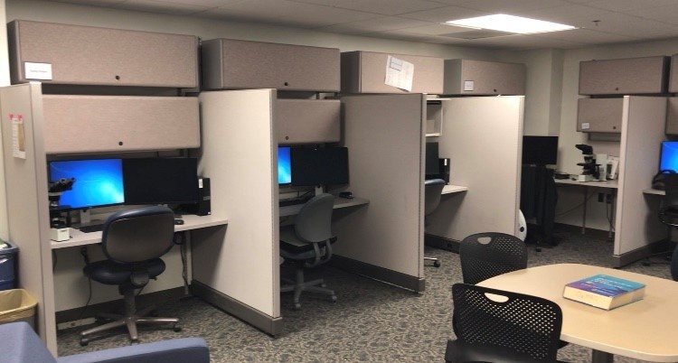 A view of the resident room featuring desks with dividers, microscopes and other equipment
