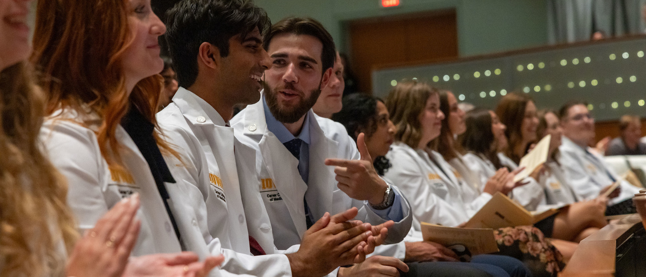 Med students at their white coat ceremony smiling