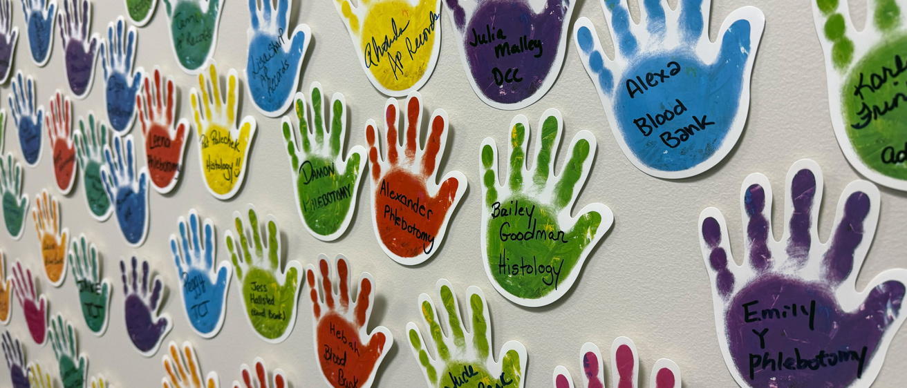 A wall full of hand stickers with handwritten names of Pathology employees on each